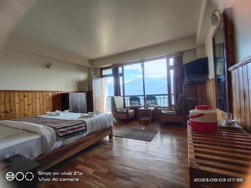 a bedroom with a bed and a large window at Hotel Hidden House (Fair View) in Pelling
