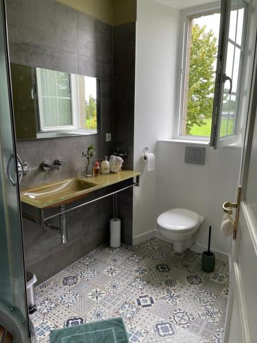 une salle de bain avec un lavabo et des toilettes dans l'établissement Le Clos du Bas Courtil Guesthouse B&B Omaha Beach, à Osmanville