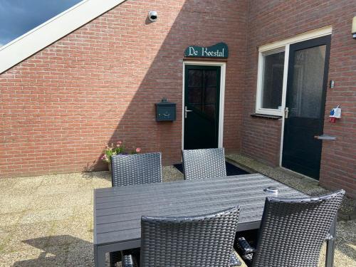 a wooden table with chairs in front of a brick building at De Koestal in Odoorn
