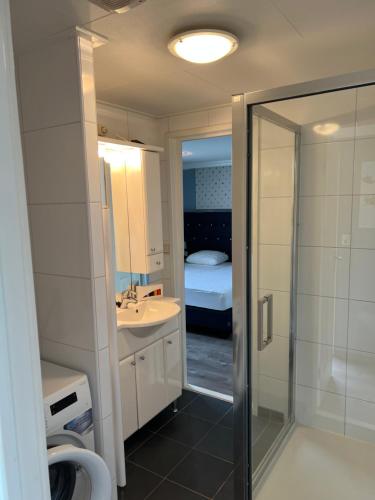 a bathroom with a sink and a shower and a bed at BLUE BEACH HOUSE in Breskens