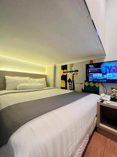 1 dormitorio con 1 cama blanca grande y TV en Front One Cabin Sunter, en Yakarta