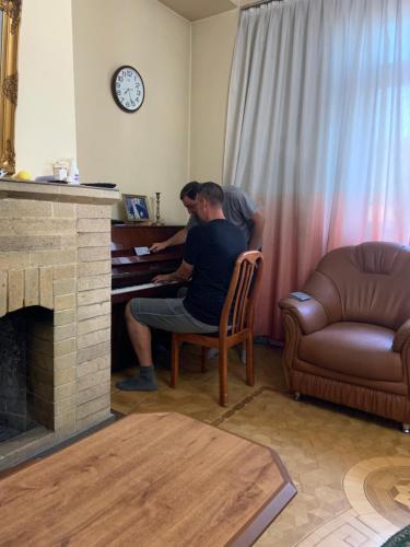 two people sitting at a piano in a living room at Guest House Lilia in Yerevan