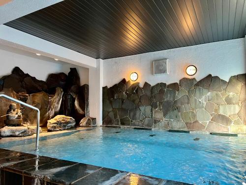uma banheira de hidromassagem num quarto com uma parede de pedra em Goyokan em Izu