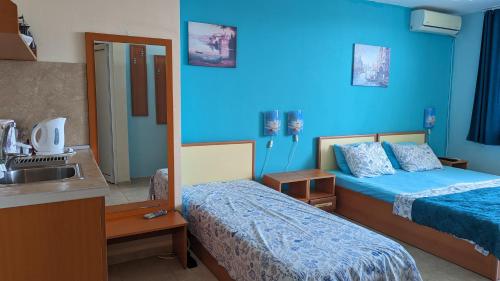 a blue room with two beds and a sink at Guest House Chalakov in Sinemorets