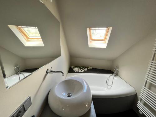 a bathroom with a sink and a tub and two windows at Ancien Cinema Loft in Vianden