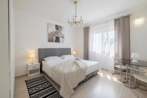 a white bedroom with a white bed and a table at Apartment Tree Of Life in Kaštela