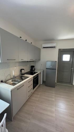 a white kitchen with a sink and a refrigerator at Harihara Guesthouse near Airport in Paianía