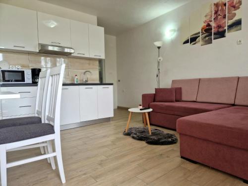 sala de estar con sofá rojo y cocina en Apartments Gabriel, en Senj