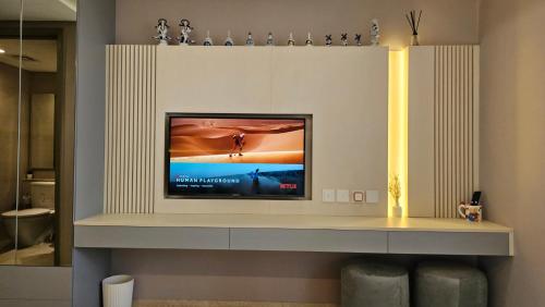 Studio Apartment at Gold Coast PIK في جاكرتا: وجود تلفزيون على رف في غرفة المعيشة