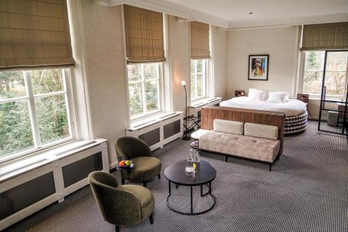 um quarto de hotel com uma cama, um sofá e cadeiras em Central Park Voorburg - Relais & Chateaux em Voorburg