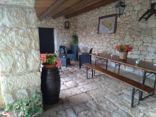eine steinerne Terrasse mit einem Holztisch und Bänken in der Unterkunft I Dammusi in Santa Croce Camerina
