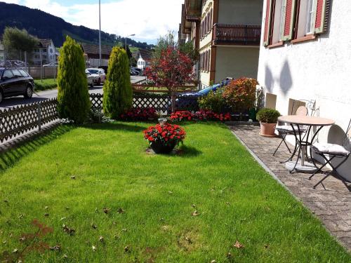 a yard with a table and a lawn with flowers at Ferienzimmer Appenzell in Appenzell