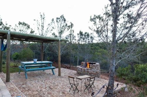a patio with a picnic table and a fire pit at The Surfers Bush Cabin in Jeffreys Bay