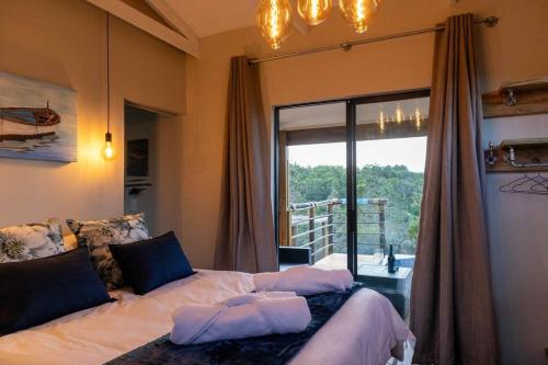 a bedroom with a bed and a large window at The Surfers Bush Cabin in Jeffreys Bay