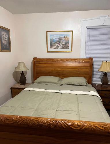 um quarto com uma cama de madeira e 2 candeeiros em Victorian Palace-Pecan Room em East Orange