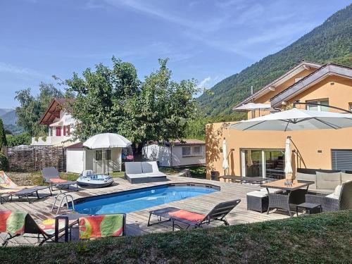 una piscina con sillas y sombrillas junto a una casa en Appartement moderne avec terrasse et piscine à Châtel sur Bex, en Bex