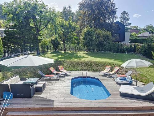a patio with a pool and chairs and umbrellas at Appartement moderne avec terrasse et piscine à Châtel sur Bex in Bex