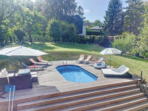 a pool with chairs and umbrellas in a yard at Appartement moderne avec terrasse et piscine à Châtel sur Bex in Bex