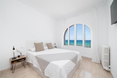 Un dormitorio blanco con una cama grande y una ventana en Preciosa casa frente al mar, en Montgat