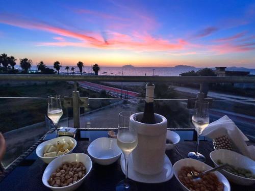a table with wine glasses and food and a view of the ocean at Residence Sunset Egadi in Marsala