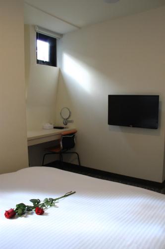 a bedroom with a bed with a television on the wall at Century Hotel in Kaohsiung