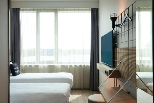 a hotel room with two beds and a television at Moxy Amsterdam Schiphol Airport in Hoofddorp