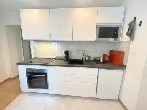 une cuisine avec des armoires blanches, un évier et un micro-ondes dans l'établissement Appartement coup de coeur Montparnasse, à Paris