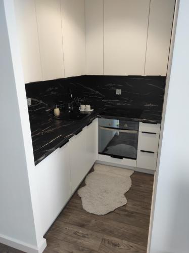 a kitchen with white cabinets and black counter tops at Klonowa 65 z garażem podziemnym in Kielce