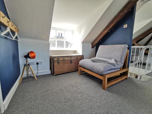 a small attic room with a chair and stairs at Stylish 2 bedroom apartment close to beaches in Fakenham
