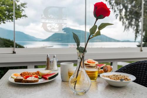 ローセンダールにあるRosendal Fjordhotelの花瓶のバラと一皿