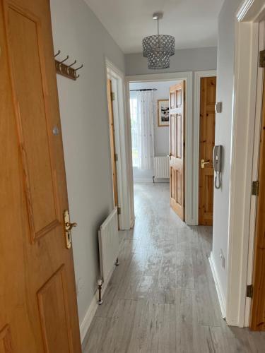 a hallway with white walls and wooden floors and a door at Garden Avenue in Portstewart