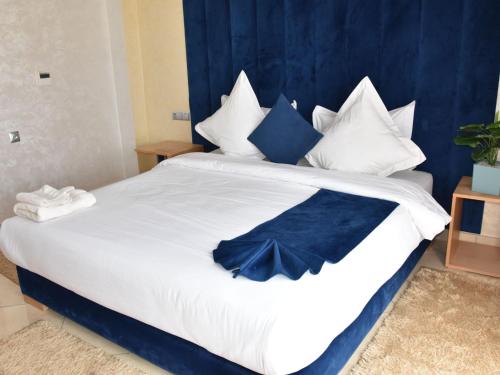 a large white bed with blue and white pillows at Perle de Souihla in Oulad Sidi Cheïkh