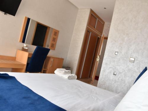 a bedroom with a bed and a desk and a door at Perle de Souihla in Oulad Sidi Cheïkh