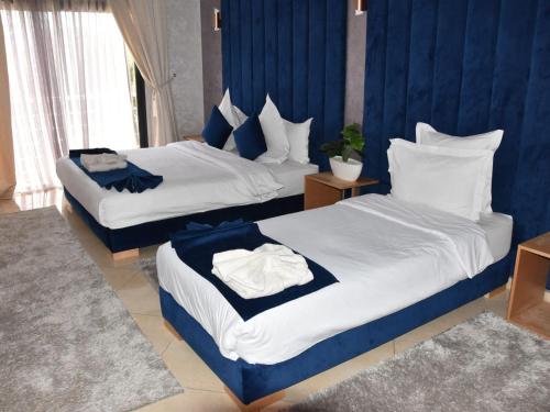 two beds in a hotel room with blue walls at Perle de Souihla in Oulad Sidi Cheïkh