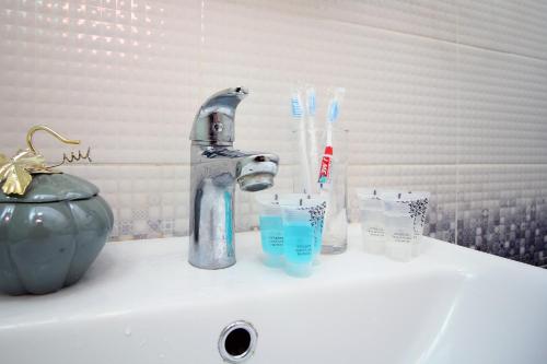 un lavabo avec un robinet et des brosses à dents et des verres dessus dans l'établissement Легенда 75, à Almaty