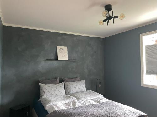 1 dormitorio con cama y pared gris en Romslig leilighet i Lofoten 