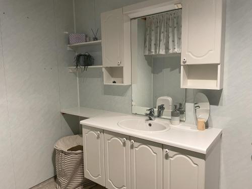 Baño blanco con lavabo y espejo en Romslig leilighet i Lofoten 