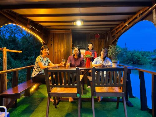 un groupe de femmes assises à une table sur une terrasse couverte dans l'établissement Homestay Phong de Pêche, à Ấp Tân Bình (1)