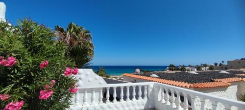 a balcony with a white fence and pink flowers at Bungalow mit Meerblick in Costa Calma