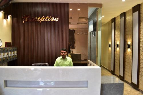 a man sitting at a reception desk in a store at Hotel Kusum Palace in Gaya