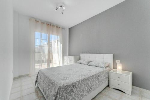 een witte slaapkamer met een bed en een raam bij Sunny Garden 1 BR Apartment Arona in Playa de las Americas