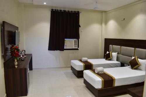 a hotel room with two beds and a desk at Hotel Kusum Palace in Gaya
