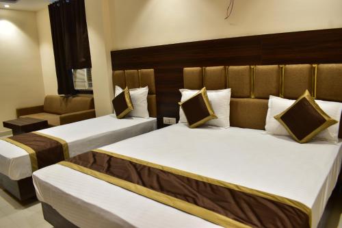a hotel room with two beds and a chair at Hotel Kusum Palace in Gaya