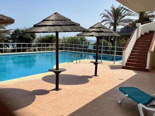 uma piscina com dois guarda-sóis e uma cadeira e uma piscina em Spacious Stunning Views 2-Bed Apartment Estepona em Estepona