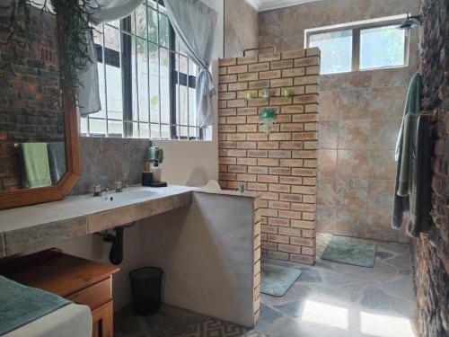 baño con lavabo y pared de ladrillo en HomeAway Beach House en Port Edward