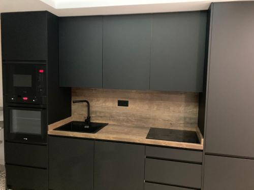 a kitchen with black cabinets and a sink and a microwave at Casa Casco Antiguo in Linares