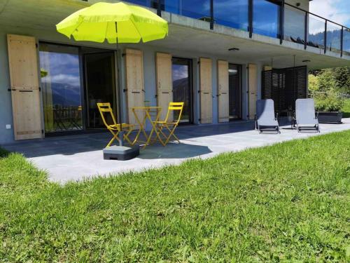 a patio with chairs and a table and an umbrella at Modern apartment with an amazing view in Leysin