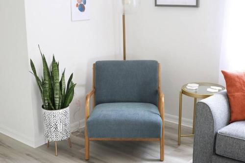 a blue chair in a living room with a plant at Sanctuary Gainesville Bright 2 BR King Condo in Gainesville