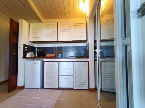 a kitchen with white cabinets and white appliances at MADIROKELY HOUSE Nosy Be in Ambatoloaka