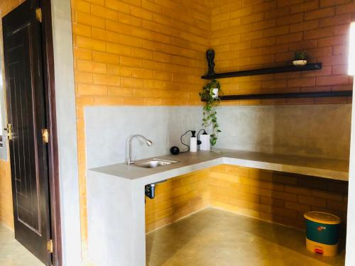 cocina con fregadero en una pared de ladrillo en Claystone Villa, en Mirissa